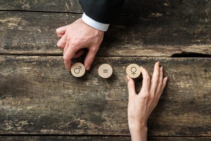 mão masculina e feminina colocando círculos cortados em madeira com símbolos de gênero